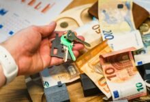 Ключи от дома в руке над банкнотами евро